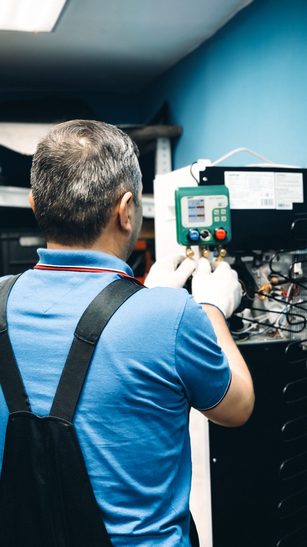 Técnico uniformado midiendo el refrigerante de un aire acondicionado con manómetro